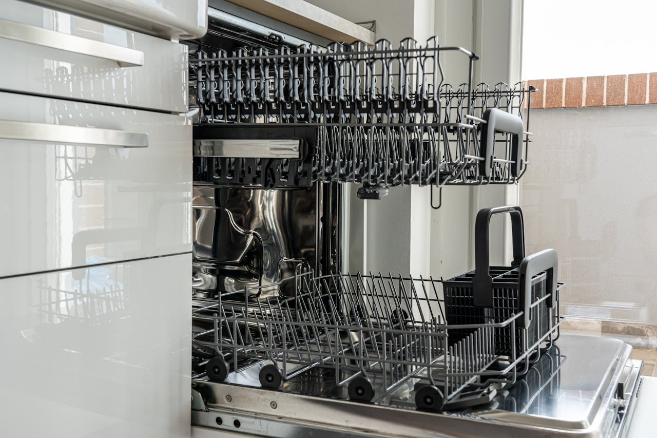 Open and empty dishwasher in a sunlit modern kitchen ready for use.