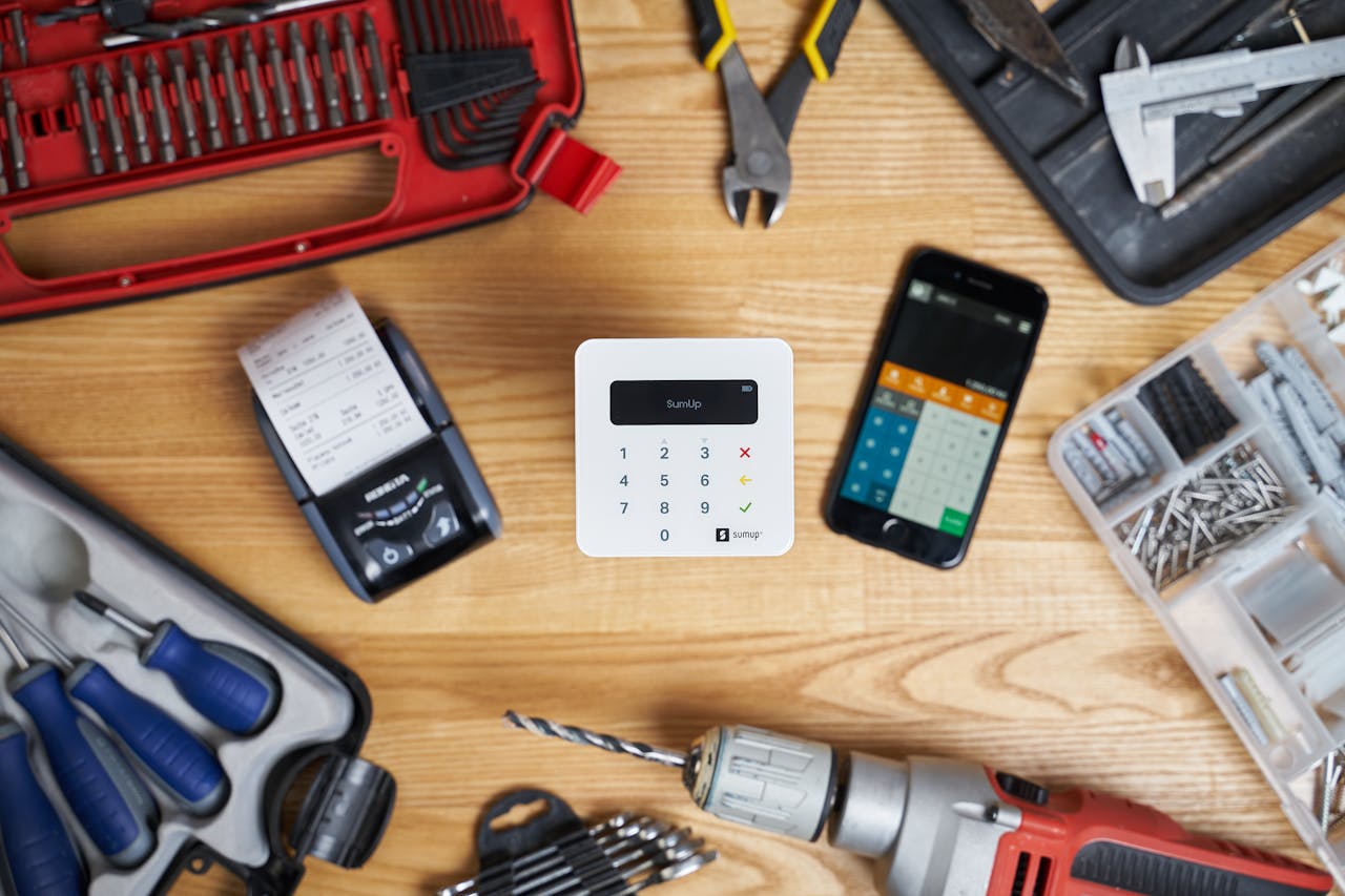 Modern cash registers and calculator on screen of smartphone among drill and pliers composing with other instrument for fixing and building